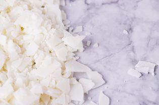 White soy wax flakes for candle making on a gray marble background