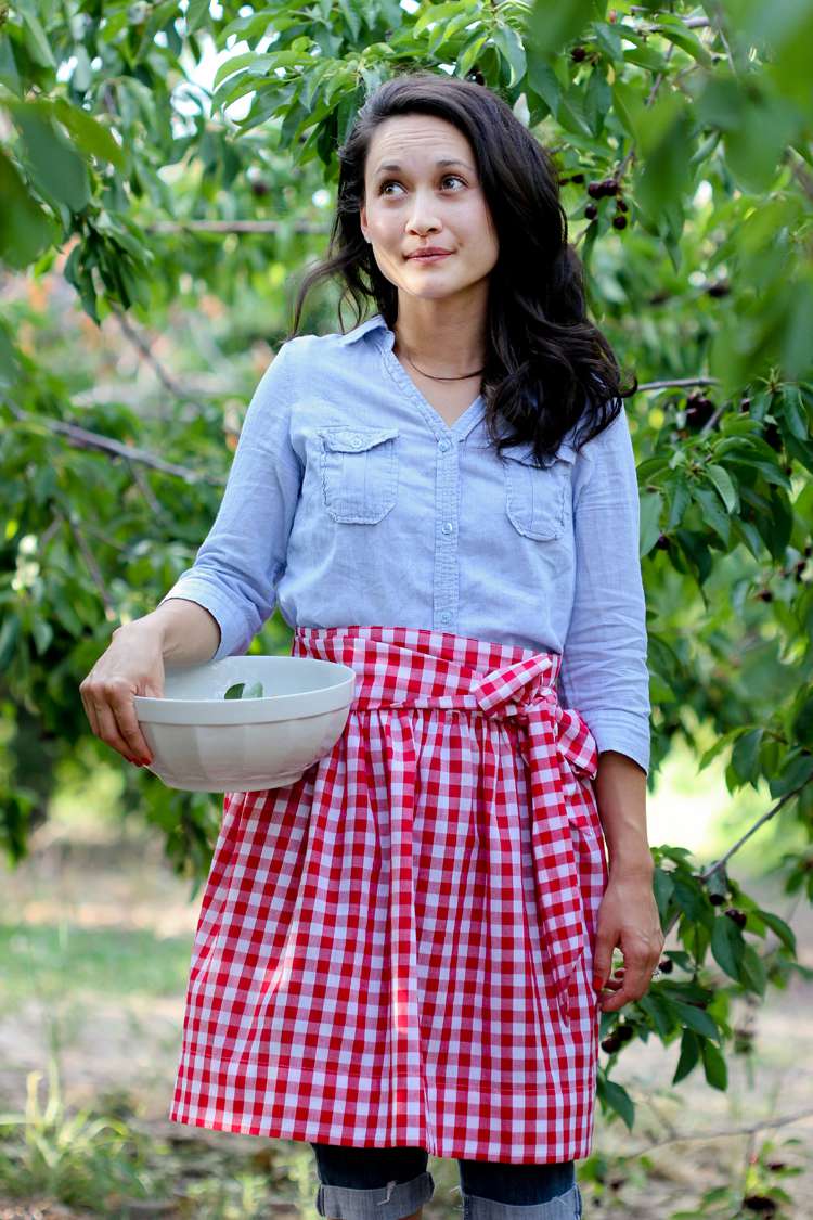 一个女人穿着红色和白色的围裙,采摘樱桃