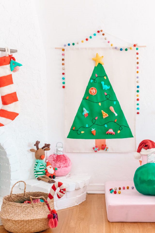 一棵毛毡圣诞树挂在墙上，旁边是孩子们的玩具。