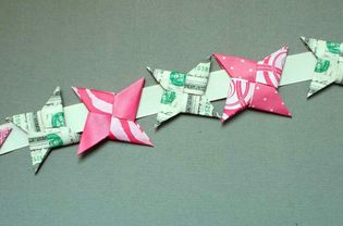 Dollar bill and origami ninja stars arranged in a row