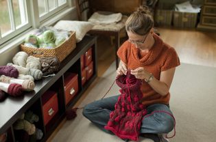 女人编织一个美丽的围巾在她的客厅。