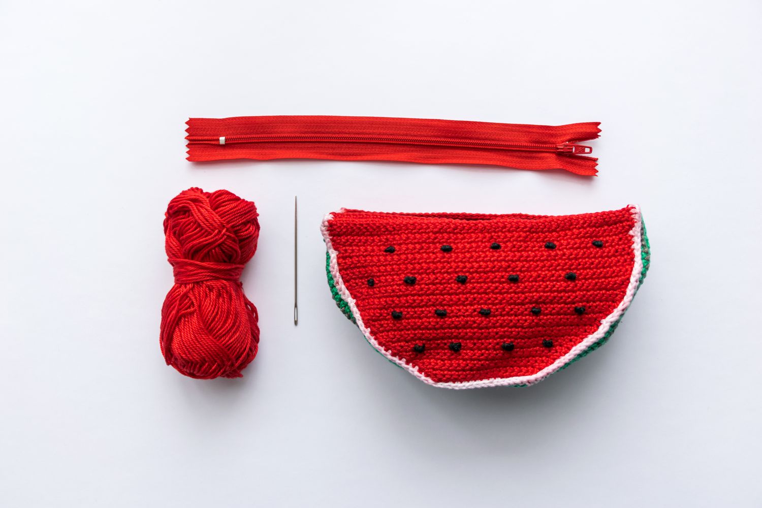 手工钩针西瓜袋与红色纱线，针和红色拉链等待被缝在