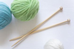 Close up of knitting needles with balls of yarn