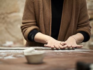 女陶工在餐桌上制作粘土卷