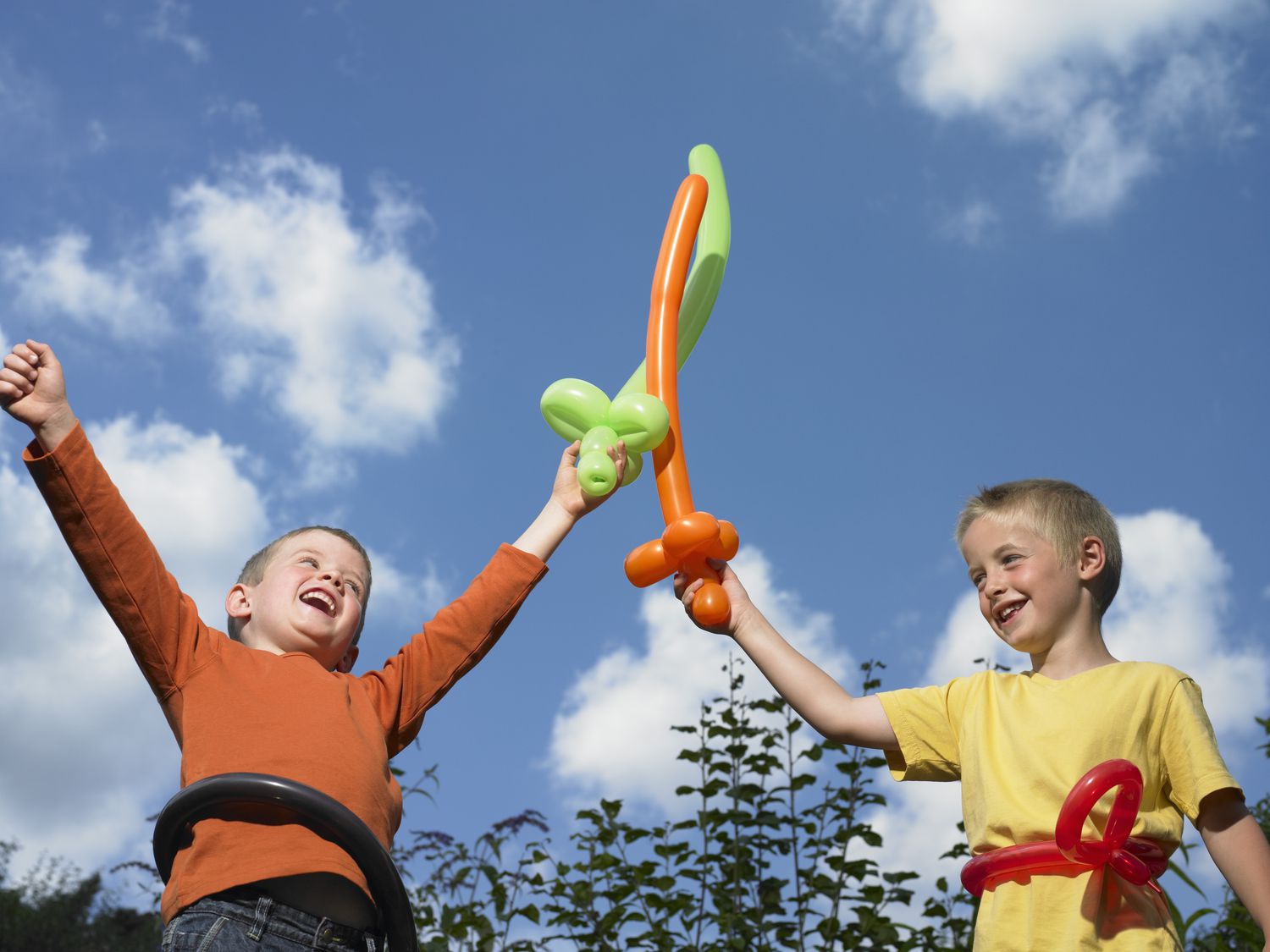 两个男孩(5 - 7)玩气球剑,笑了,低角度的观点