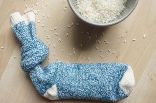 A blue sock filled with rice on a light wood background.