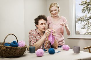 A woman teaches a man to knit