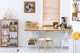 一个创意房间的真实照片，有一张桌子，线，针织羊毛和图形在墙上