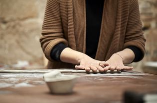 女陶工在餐桌上制作粘土卷