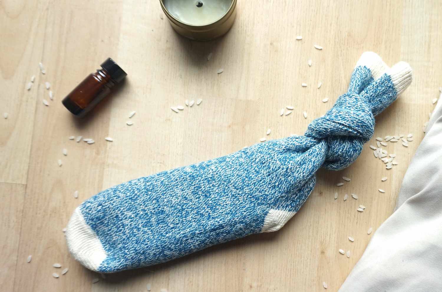 DIY加热垫由浅色的背景上的袜子粒大米,一瓶精油和一个小蜡烛。