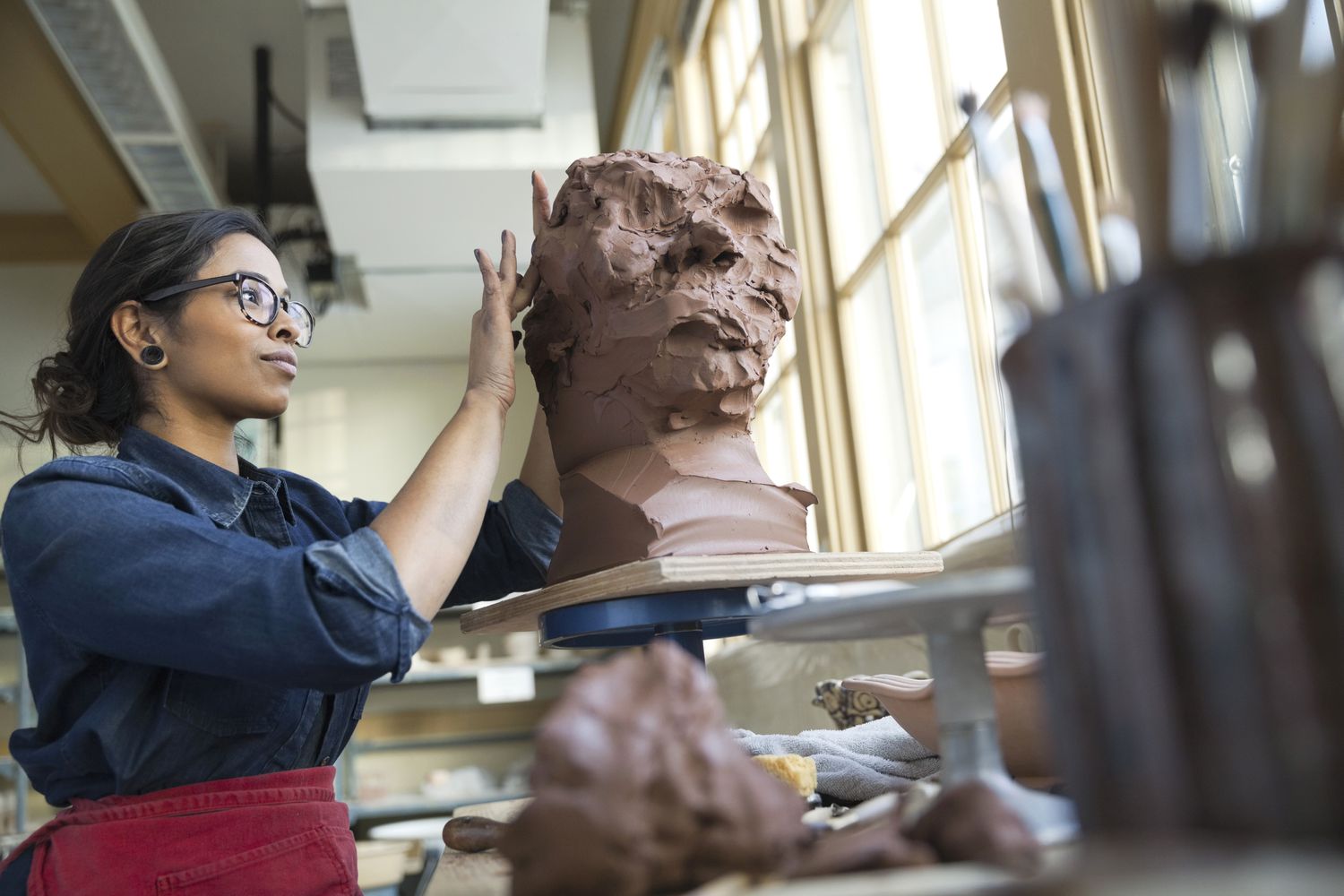 在陶瓷艺术工作室里，艺术家用石膏棒在粘土上雕刻一张脸
