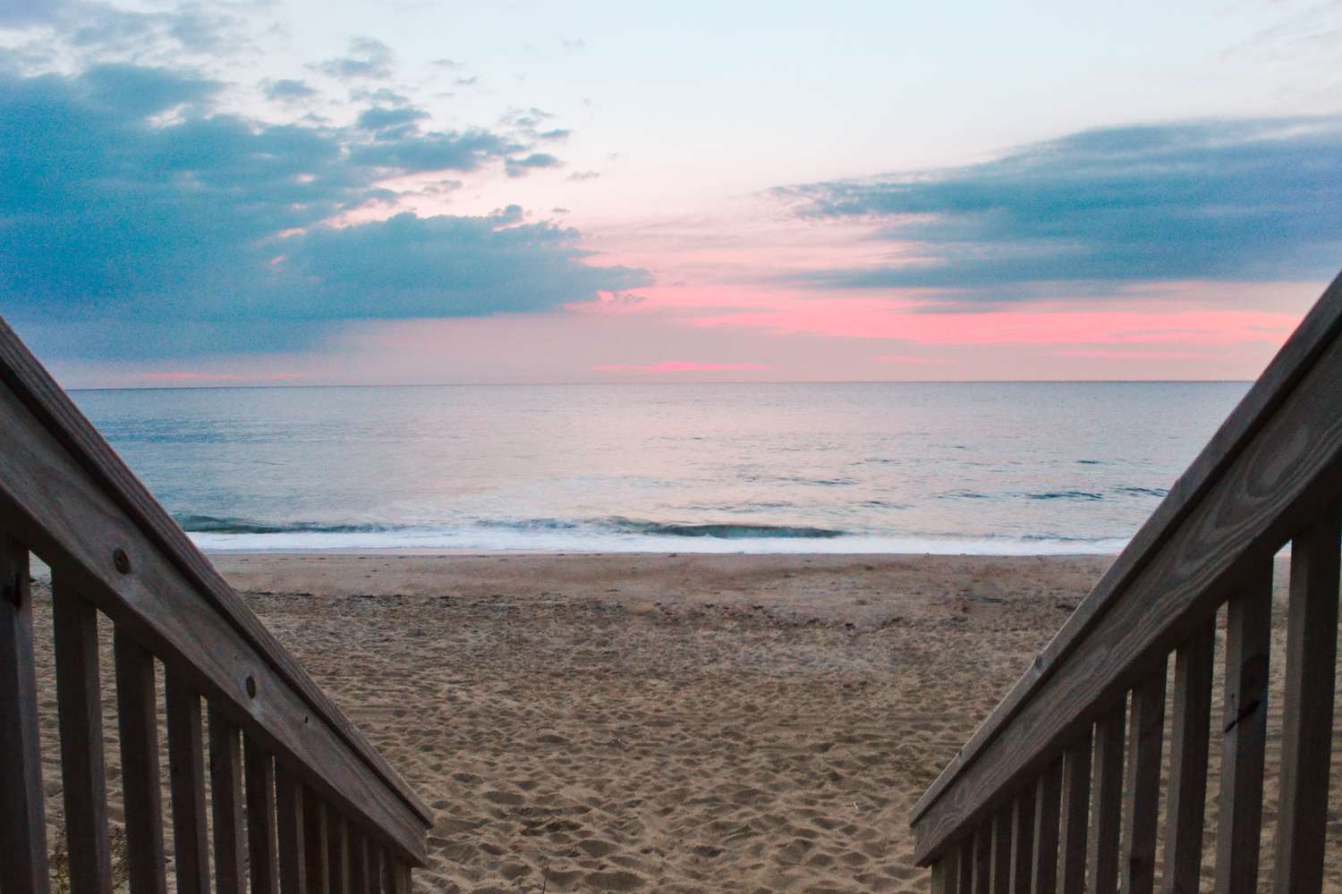 Wood railings on each side facing toward beach with blue and pink sunrise