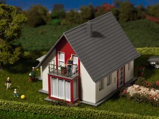 A diorama of a family of miniature figurines and their dollhouse