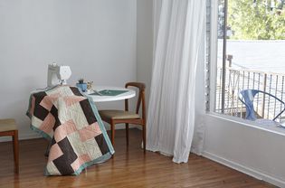 Quilt in sewing machine on table by window