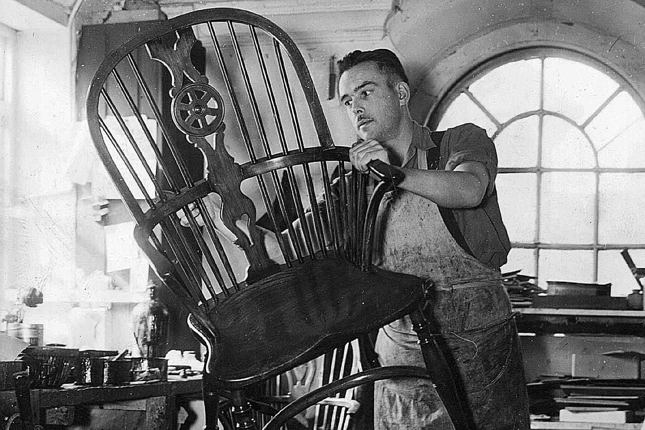 A man French at Messrs Nicholls & James, High Wycombe, Buckinghamshire, polishes a Windsor armchair for export to the USA.