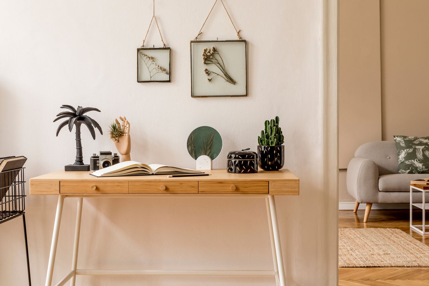 斯堪的纳维亚开放空间的室内设计，有模拟相框，木桌，灰色沙发，仙人掌，书籍办公室和个人配饰。时尚中性的家居舞台。米色墙。模板。