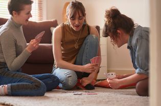 3 girls playing card game in living room
