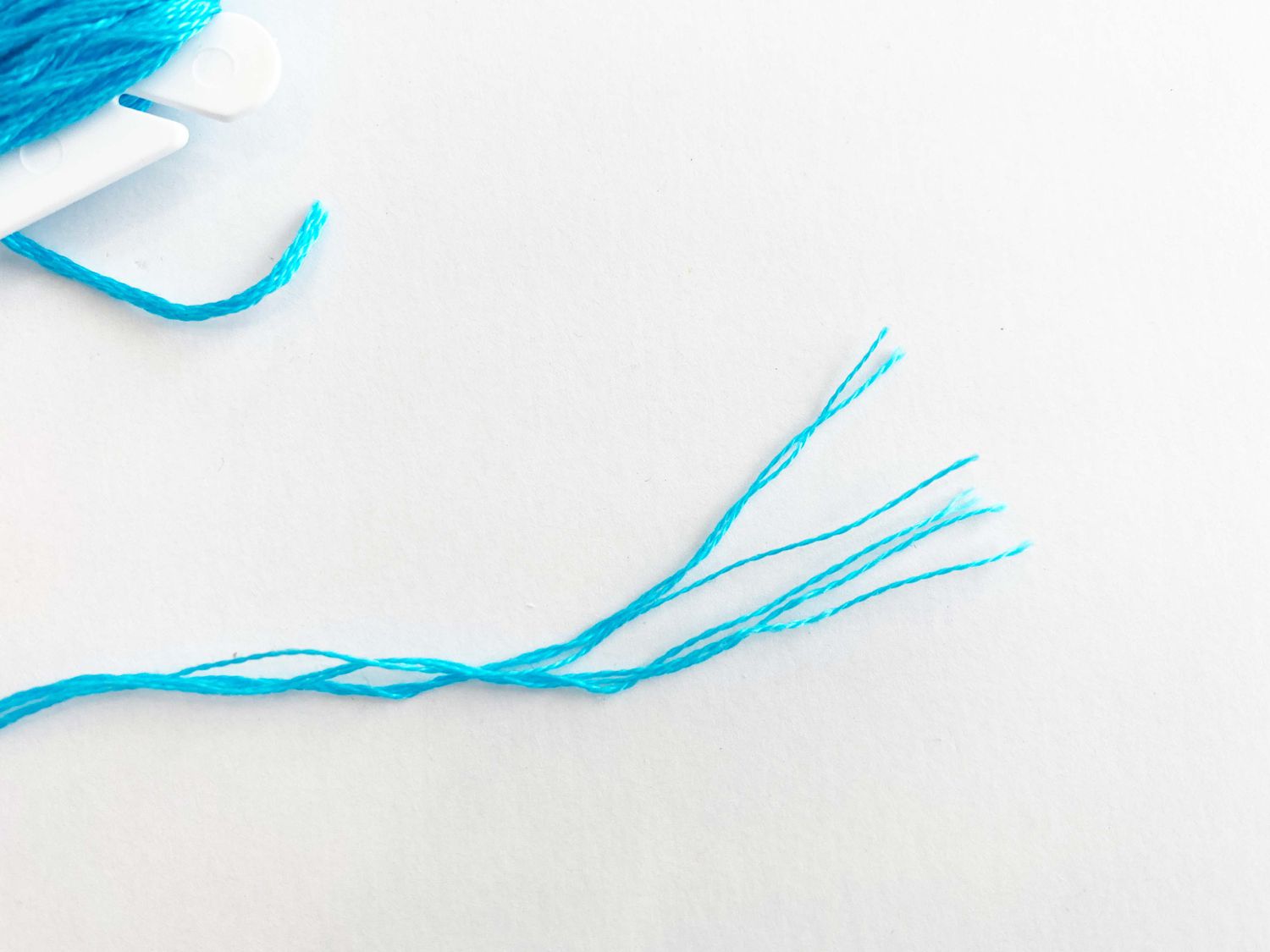 A close-up of embroidery floss divided up into strands