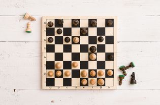 在白色木桌背景上的游戏中，木制棋盘上的人物俯视图