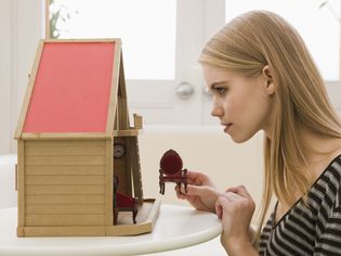 Young Woman Looking at Dollhouse