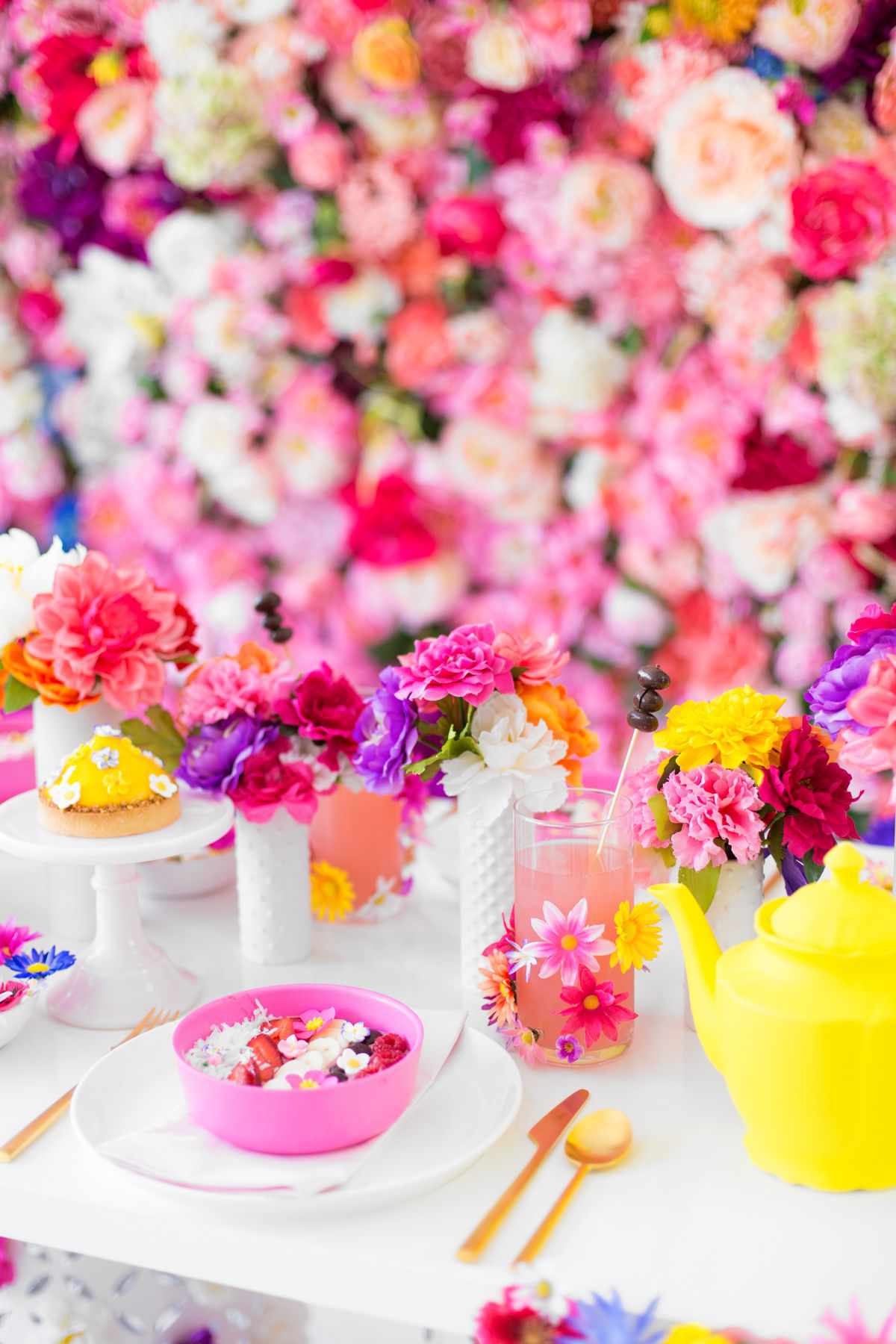 五颜六色的花装饰着墙壁，桌子上的花和黄色的茶壶。