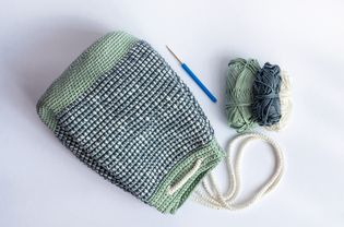 自制,钩针编织的马赛克缝合,桶袋背包在柔和的绿色,白色和灰色与白色钩针编织绳为关闭