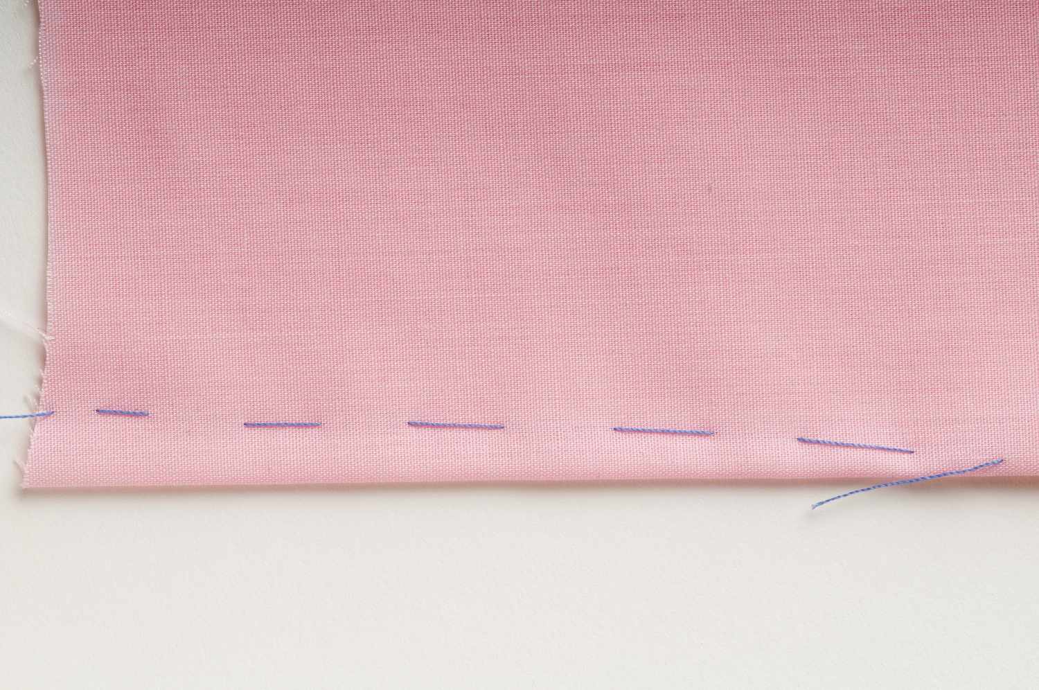 Dart marked out with basting stitch, on pink fabric, close up