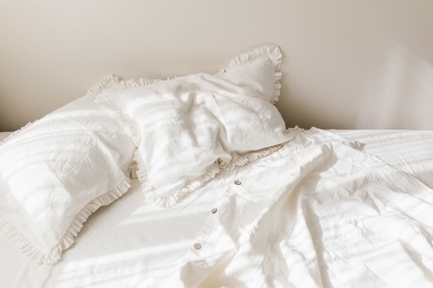 在早晨灿烂的阳光下，清空白色亚麻被褥和皱褶枕头。