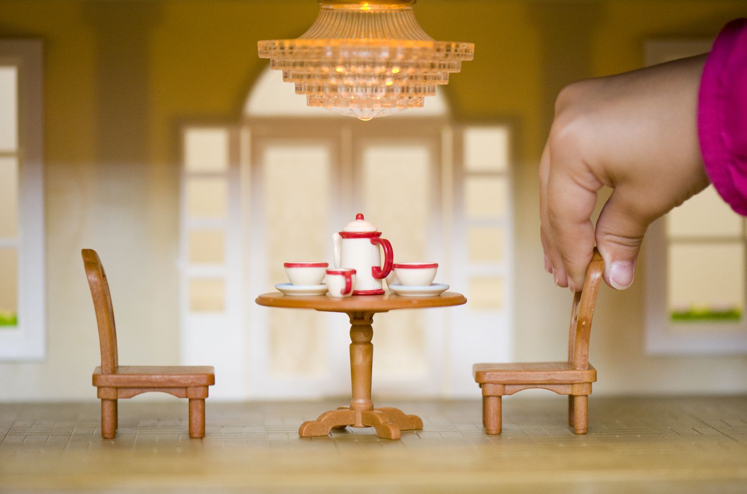 Close up of child's hand in a dolls house
