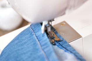 Sewing denim jeans with sewing machine. Repair jeans by sewing machine.
