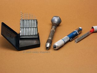 A set of miniature drills in a drill index, along with a revolving head pin vice and a mini drill.