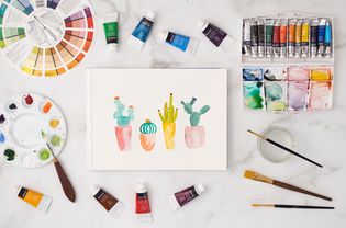 Watercolor painting surrounded with paint, brushes, tray and color wheel