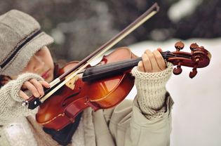 女人穿着露指手套,拉小提琴。