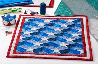 Completed quilt with stylized elements of American flag, patchwork tools