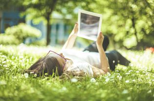 Woman looking at image while lying in the grass.