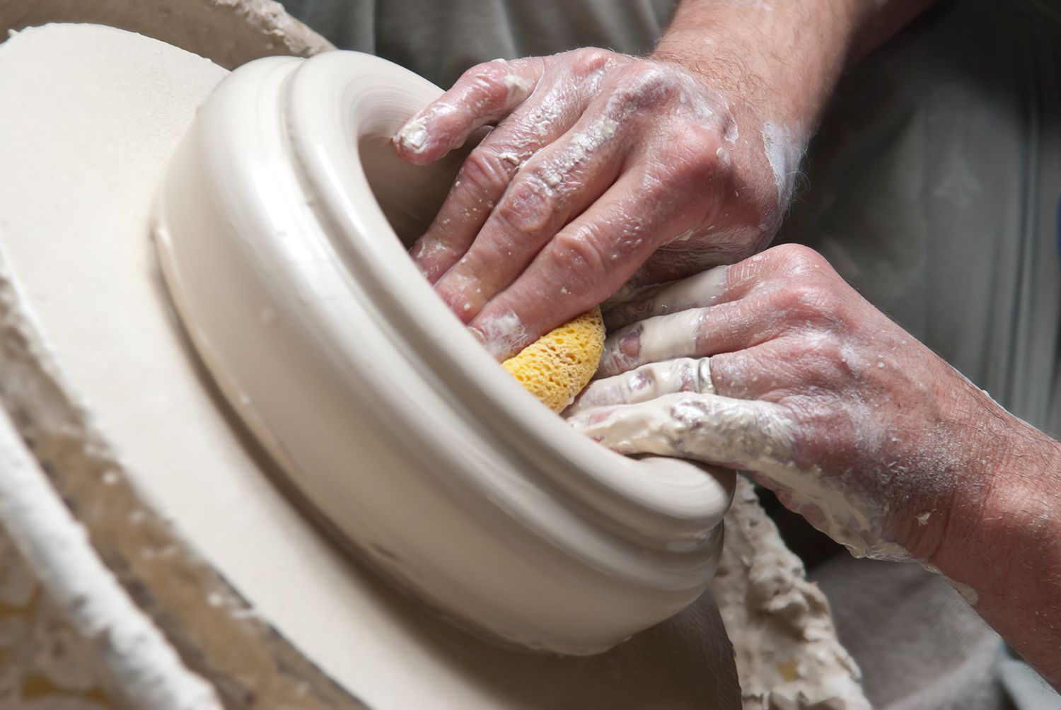 陶工用海绵在陶轮上塑形碗。
