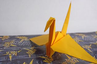Yellow origami crane sitting on a table.