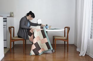 妇女在家里用缝纫机缝被子