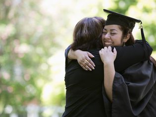 西班牙裔母亲拥抱的大学毕业生的女儿