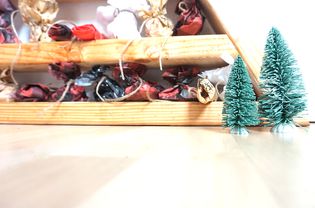 A close up of a DIY wood advent calendar with mini bottle brush trees in front of it.
