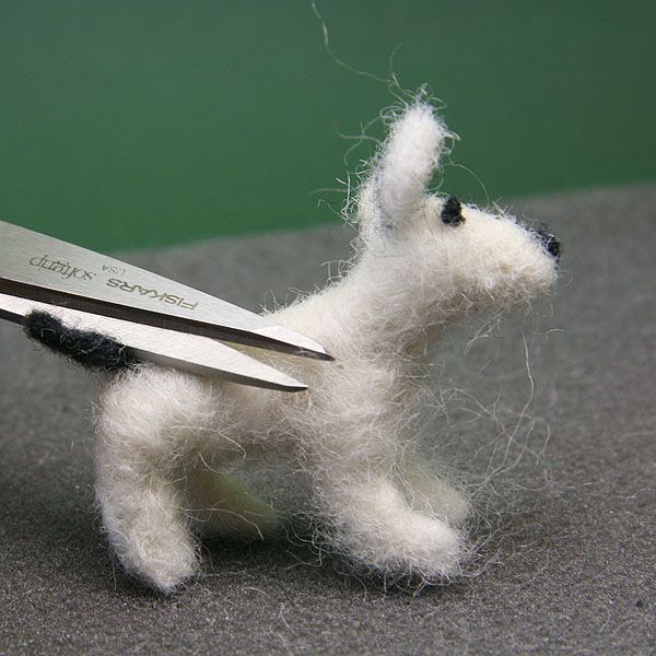 剪刀修剪松散纤维从规模娃娃家的身体缩绒狗。
