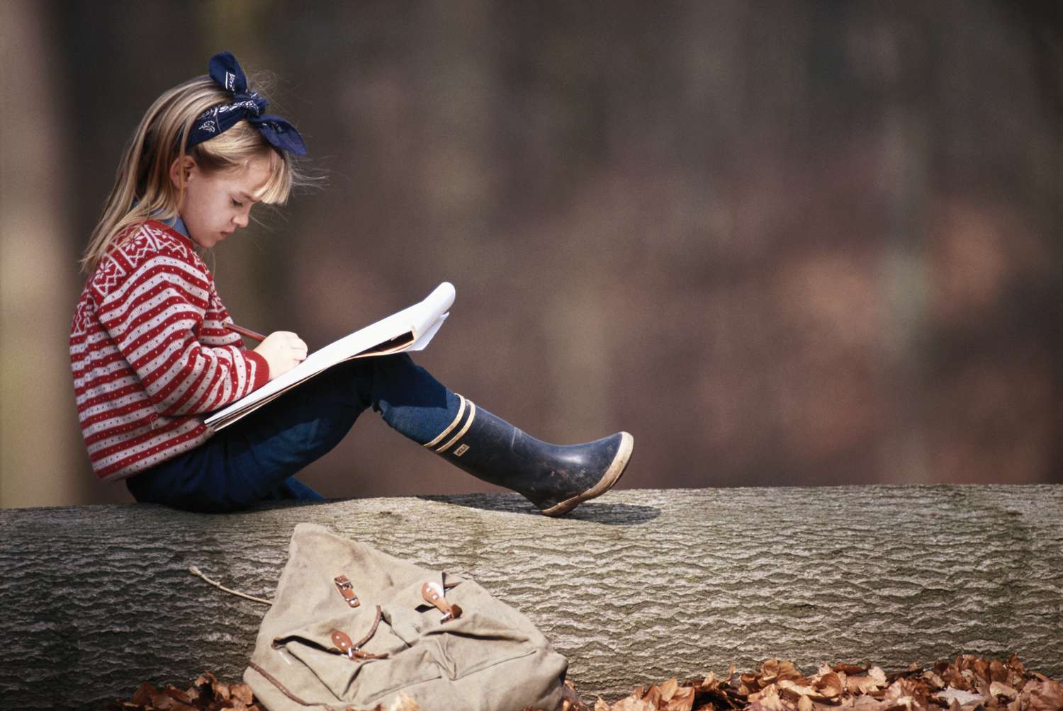 女孩(6-7岁)坐在树枝上写字，侧视图