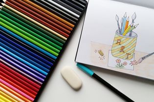 在桌子上用多色铅笔在纸上绘图的高角度视图