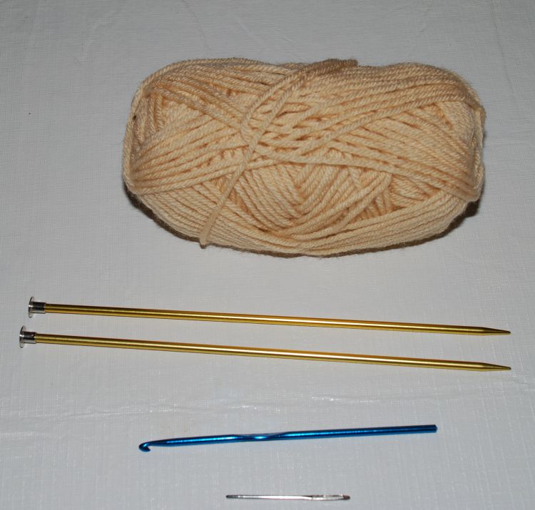 Supplies for your first knitting project, including yarn, needles, and hook