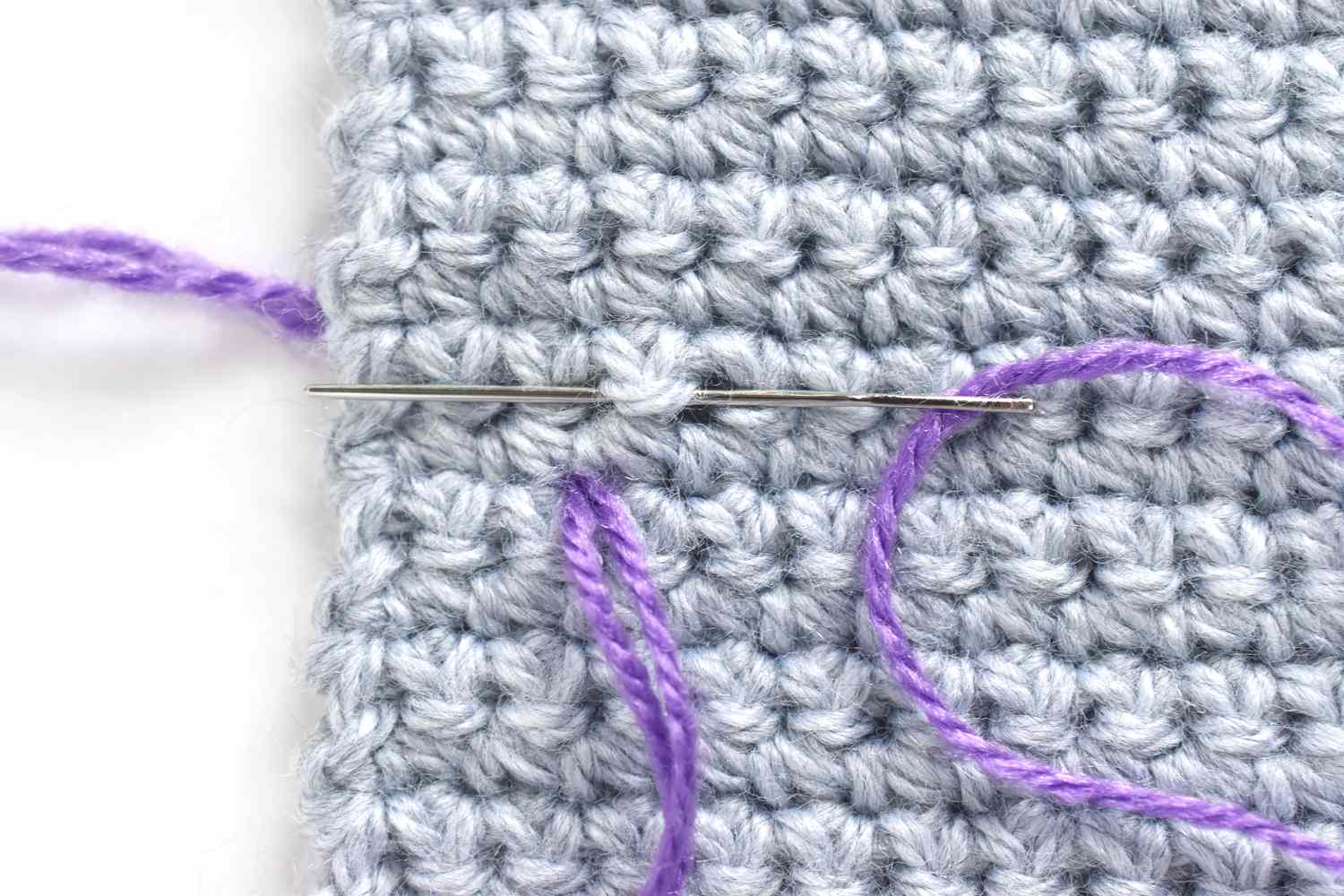 灰色纱线上的针和紫色线