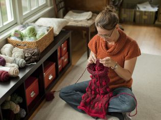 女人编织一个美丽的围巾在她的客厅。