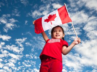 一个5岁的女孩微笑着拿着加拿大国旗