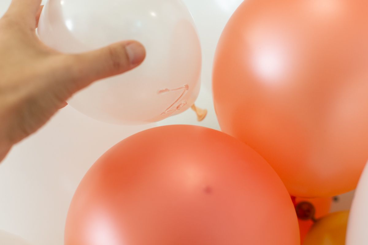 一只手用胶水把另一个气球放进去，以填满气球的拱形