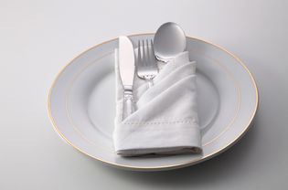 白色背景上盘子里的餐具和餐巾的高角度视图