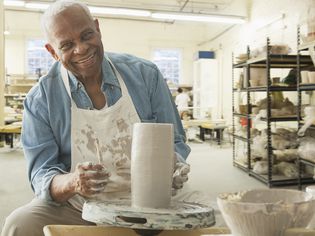 年长的黑人在工作室用轮子制作陶器